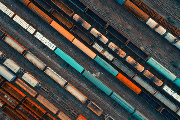 Naklejka premium Aerial view of colorful freight trains on the railway station. Cargo trains close-up. Wagons with goods on railroad. Heavy industry. Industrial conceptual scene with trains. Top view. Vintage style