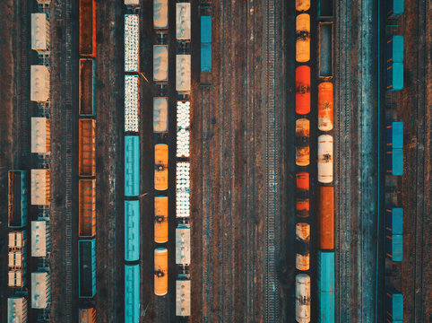 Aerial view of colorful freight trains on the railway station. Cargo trains close-up. Wagons with goods on railroad. Heavy industry. Industrial conceptual scene with trains. Top view. Vintage style