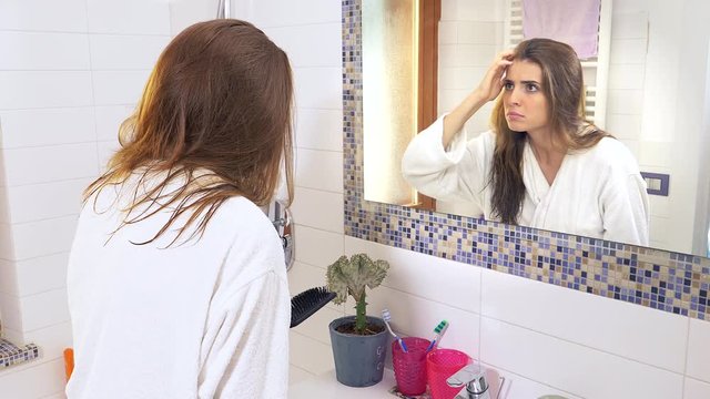 Woman in bathroom horrified by receiding hairlines desperate