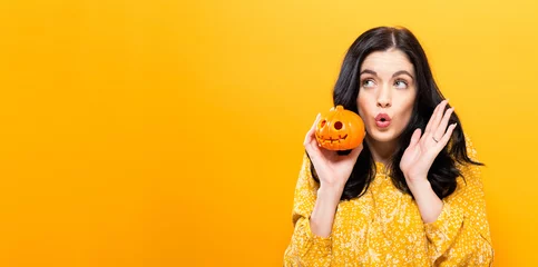 Fototapeten Young woman holding a pumpkin in halloween theme © Tierney