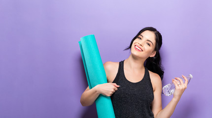 Happy young woman holding a yoga mat