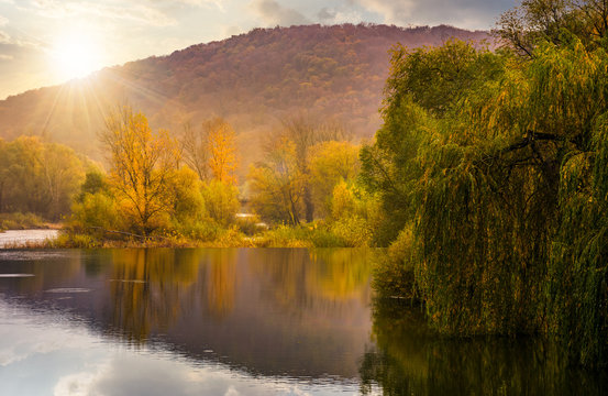 landscape with calm river in autumn at sunset. beautiful mountainous scenery with red and yellow foliage
