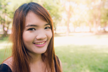Fototapeta premium Calm beautiful smiling young woman with ponytail enjoying fresh air outdoor, relaxing with eyes closed, feeling alive, breathing, dreaming. Copy space, green park nature background. Side view portrait