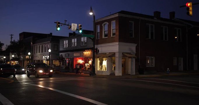 A nighttime establishing shot of businesses on a typical Main Street in America. Pittsburgh suburb.	Building names and addresses obscured.  	