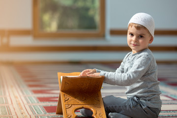 The Muslim child prays in the mosque, the little boy prays to God, Peace and love in the holy month...