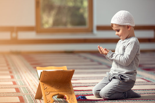 The Muslim child prays in the mosque, the little boy prays to God, Peace and love in the holy month of Ramadan.