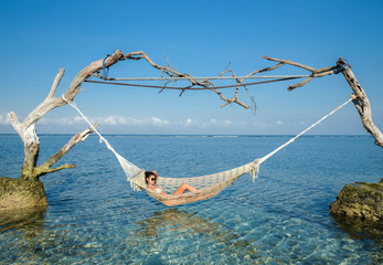 Woman relaxing in the swing in the paradise turquoise sea, Gili Trawangan island, Indonesia