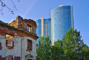 The old destroyed building against the backdrop of a new multi-storey skyscraper.
