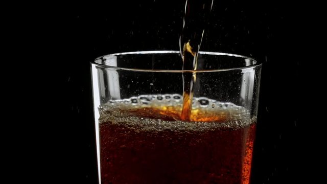 Pouring refreshing ice cold Cola in a glass