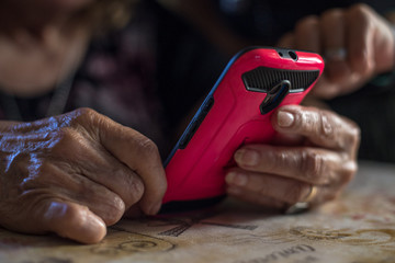 Old male hands with smartphone texting message, at home. Close up  of senior woman hands.  