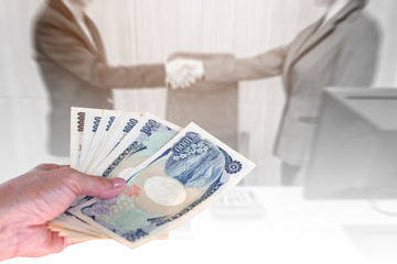 hand woman with Japanese currency yen bank notes on blurred background two business shake hand at office