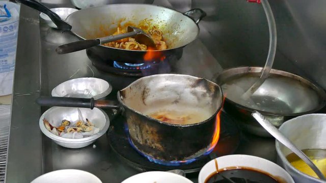 chef cooking spicy Thai food in kitchen 