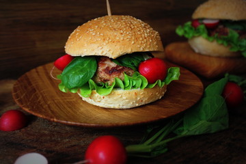 Homemade traditional burgers with beef,radish,lettuce, served on wooden background.