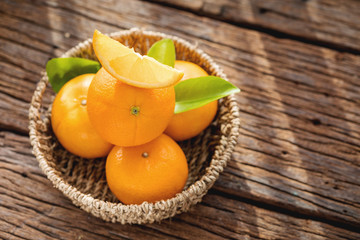 Fresh orange fruits in basket on wood table.