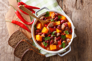 Stew with beef, pumpkin, red beans, tomatoes and chilli close-up in a pot. Horizontal top view