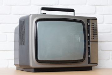 Old television on a white brick wall background.