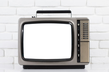 Old television with cut out screen on a white brick wall