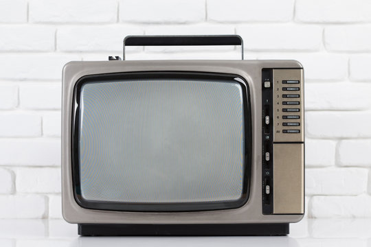 Old television on a white brick wall background.