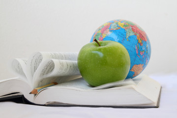 green apple on a open book with  world map isolated on white