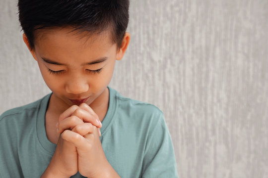 asian boy child praying with eyes closed, christianity faith concept