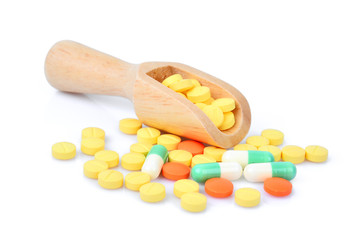pill and capsules in wooden scoop isolated on white background