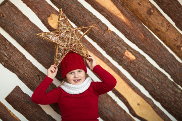 funny girl child in red hat with star, lifestyle, real interior, winter rustic style