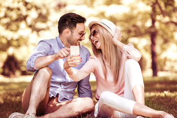 Young couple making selfie with mobile phone in the park