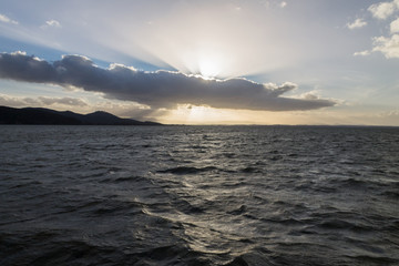 Powerful sun rays coming out through some clouds over a lake