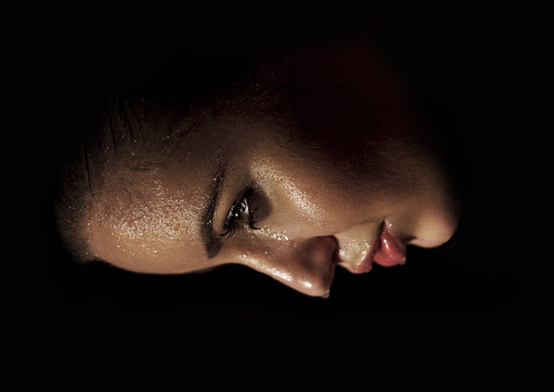 Wet face of beautiful young woman in the dark from profile with big lips
