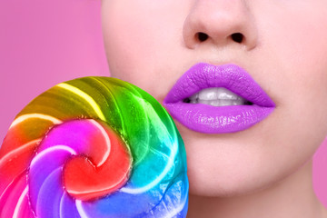Face of beautiful young woman with lollipop on color background, closeup