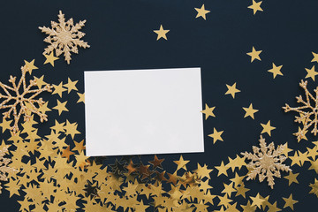 Christmas mock up greeting card on black background with glitter snowflakes ornaments gold stars confetti. Invitation, paper. Place for text flat lay