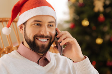 Close up of smiling man in Santa hat calling someone