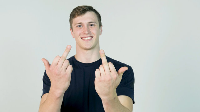 Young Man Showing Middle Finger Isolated on White. Young angry man with black t-shirt looking at camera and showing two middle finger