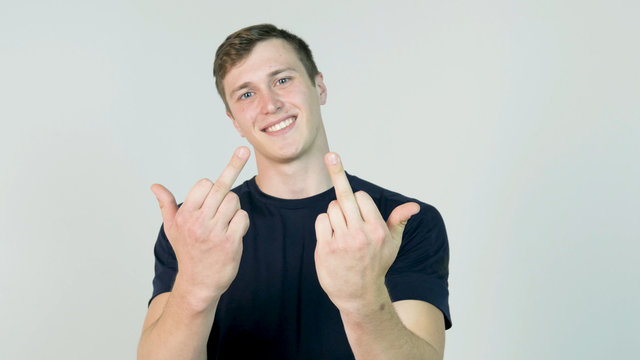 Young Man Showing Middle Finger Isolated on White. Young angry man with black t-shirt looking at camera and showing two middle finger