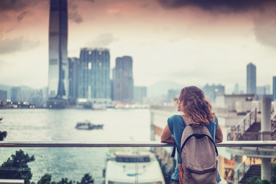 tourist woman on background of a big city with skyscrapers, looking at the sunset