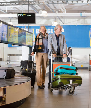 Senior Business Couple With Luggage In Cart At Airport