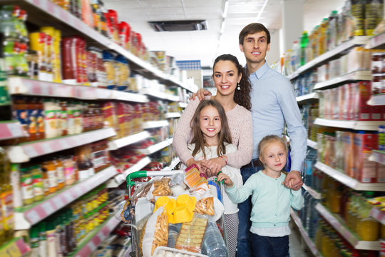 Adult smiling family with two daughters shopping