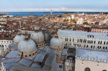 Fototapeta na wymiar Domes of St Mark's church and traditional venetian houses with clay tiled red roofs, Venice, Italy. An aerial top-view from Campanile di San Marco