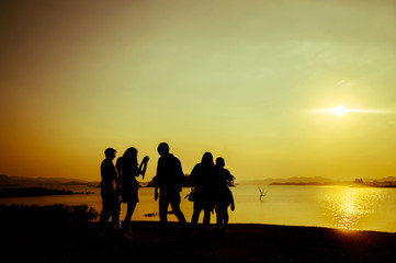 Fototapeta na wymiar The silhouette of group of peoples near the water during sunset time