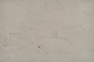 Gray-white surface of a wall with cracked paint, plaster, close-up 