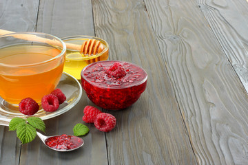 healthy background. raspberry with raspberry jam, honey and tea on dark wooden background