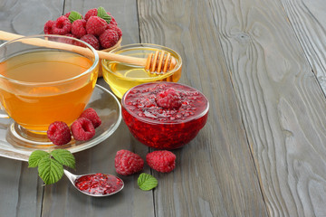 healthy background. raspberry with raspberry jam, honey and tea on dark wooden background