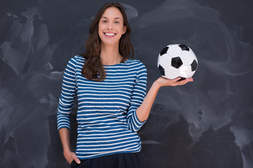 woman holding a soccer ball in front of chalk drawing board