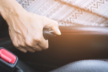 Closeup of person hand pulling handbrake lever in car For safety while parking.