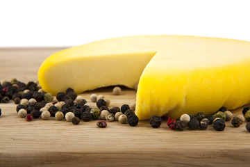 Cheese on a wooden table and pepper isolated on white background