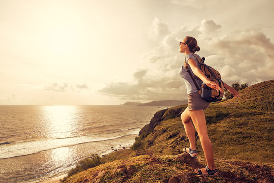 woman traveler with backpack enjoying sunset view on the mountain coast