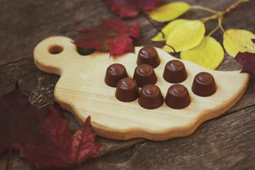 chocolate candies on a wooden Board with autumn leaves