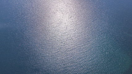 Vista aerea delle acque blu del mar Mediterraneo e nello specifico del mar Tirreno. La luce del sole si riflette sulla superficie dell'acqua.