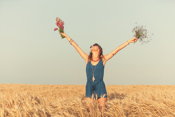 Girl holding flower bouquet in the wheat field.