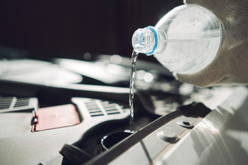 Close-up. The man is fixing the car. Fills the water in the tank